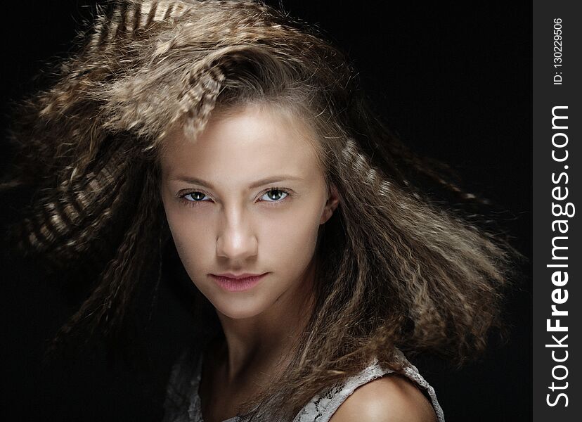 Close up portrait of young blond woman with curly hair over black background