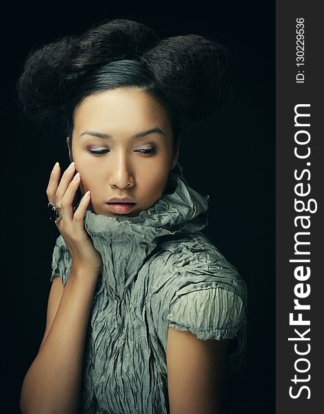 Beauty and fashion concept: young Asian fashion model in grey dress against black background