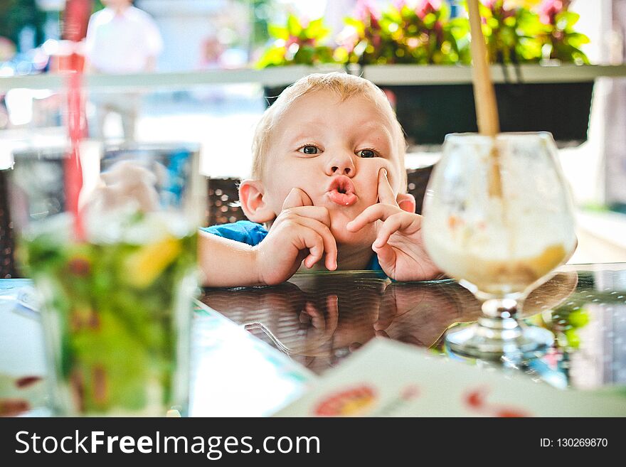 Boy drinking milk cocktail with a straw in a cafe. Boy drinking milk cocktail with a straw in a cafe