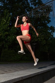 Young Happy Woman Running Outdoor In A City Park. Girl Running Running In The Nature To Lose Weight And Maintain A Stock Photo