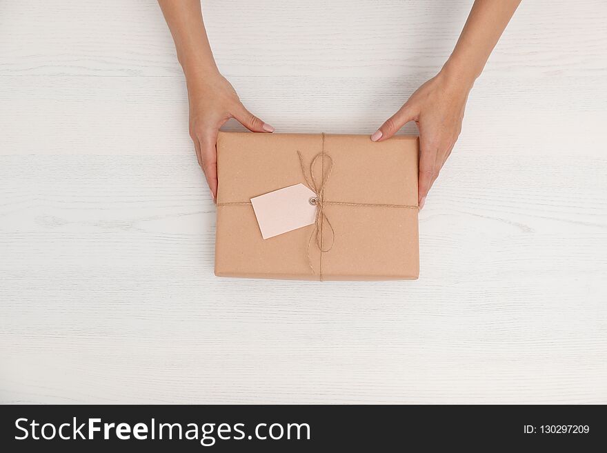Woman holding parcel with tag on wooden background