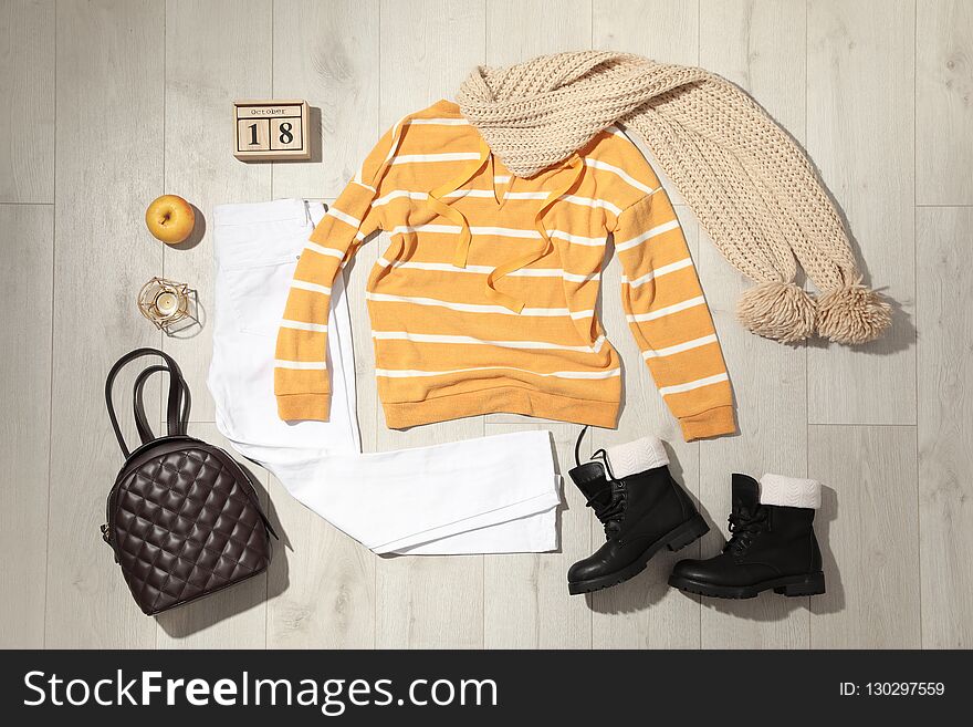Set of stylish winter outfit on wooden background, flat lay
