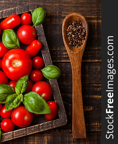 Organic Tomatoes with basil and pepper on spoon in vintage wooden box on wooden kitchen table