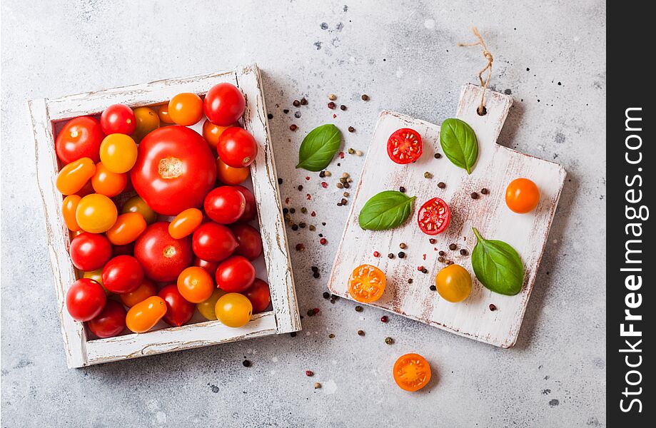 Organic Tomatoes with basil in vintage wooden box on stone kitchen table background. San Marzano, orange and plum tomatoes
