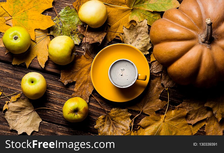 Fallen leaves, pumpkin, apples and cup of coffee