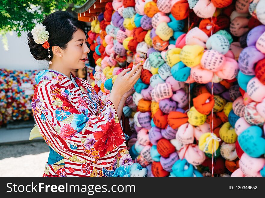 Japanese girl with traditional clothes hanging her praying ball on the colorful blessing wall. attractive young girl wearing ladies kimono in Kyoto. traditional lifestyle in Japan. Japanese girl with traditional clothes hanging her praying ball on the colorful blessing wall. attractive young girl wearing ladies kimono in Kyoto. traditional lifestyle in Japan.