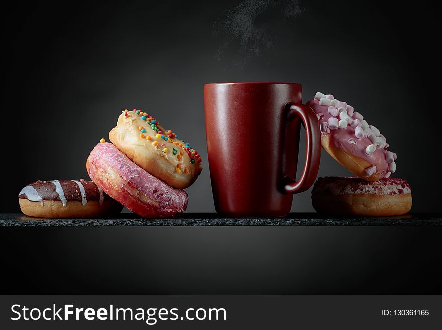 Various sweet donuts with mug on a black background. Various sweet donuts with mug on a black background.