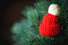 Merry Christmas And Happy New Year. Little Knitted Hat On The Christmas Tree. Background With Copy Space. Stock Photo Merry Christmas And Happy New Year. Little Knitted Hat On The Christmas Tree. Background With Copy Space. Stock Photo