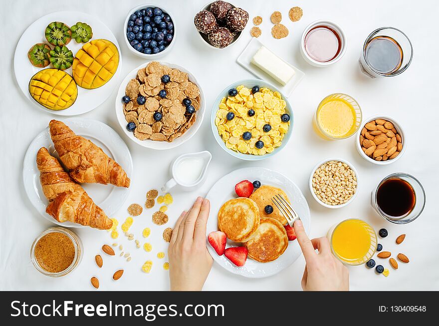 Breakfast table setting with flakes, juice, croissants, pancakes and fresh berries. toning. selective focus