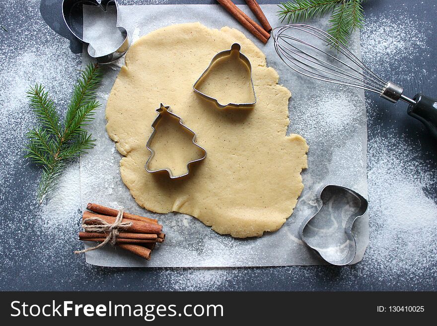 Christmas cookies. Cutting gingerbread. The process of baking cookies at home. Gingerbread dough for cookies, cookies, cinnamon sticks, orange and fir branches. New year or winter holidays still life, background. Top view. Christmas cookies. Cutting gingerbread. The process of baking cookies at home. Gingerbread dough for cookies, cookies, cinnamon sticks, orange and fir branches. New year or winter holidays still life, background. Top view