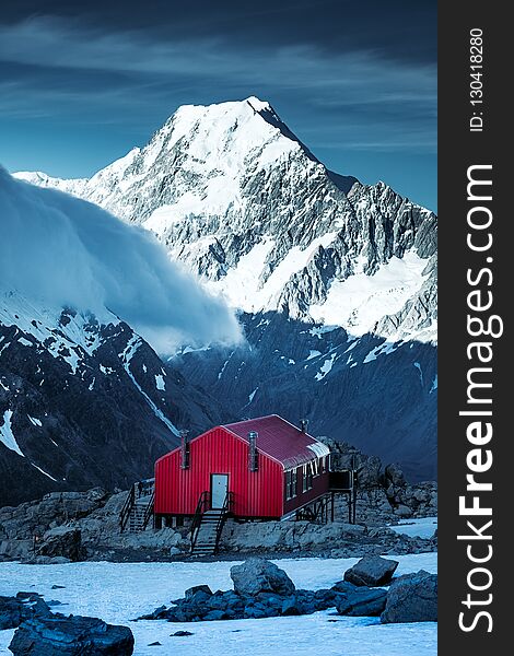 Winter landscape view of red mountain hut and Mt Cook peak in the background, New Zealand. Winter landscape view of red mountain hut and Mt Cook peak in the background, New Zealand