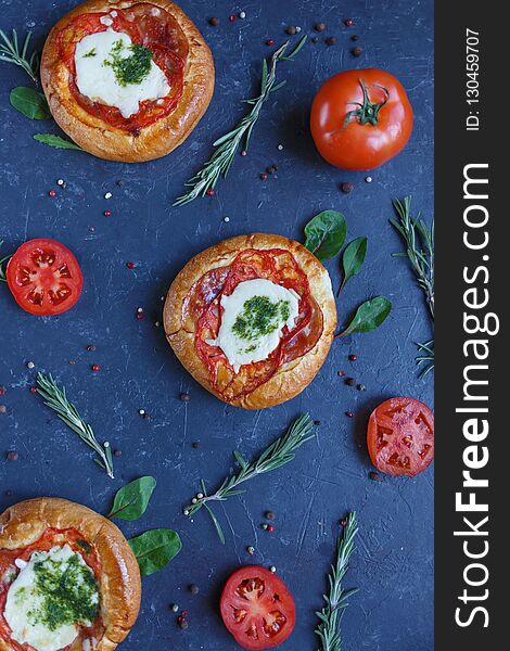 Three Homemade Mini Pizza with Tomatoes, Cheese and Bacon, Injuries and Spices on Dark Background Vertical