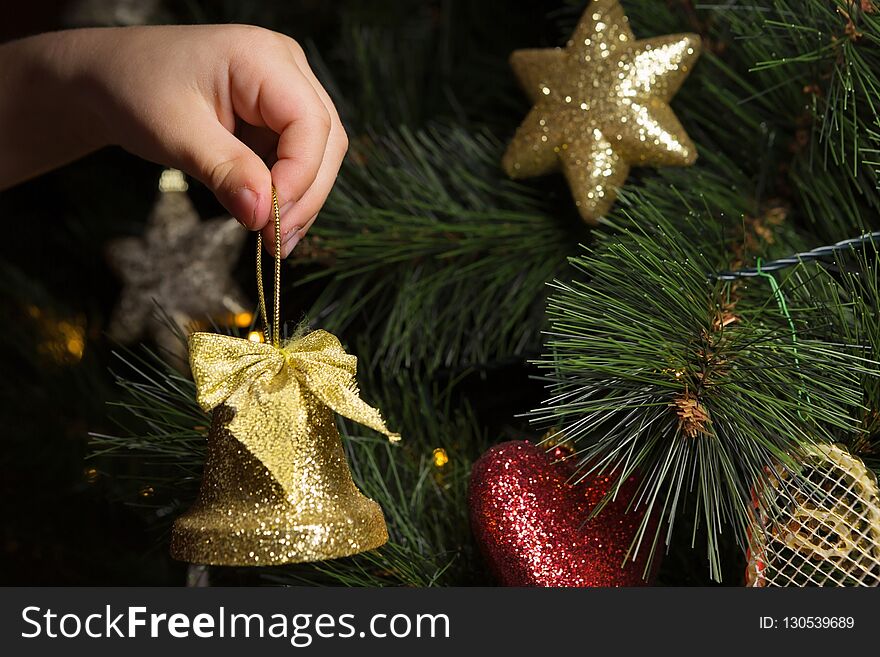 Close-up of Childâ€™s Hand Putting a Christmas Ornament on the Tree. Close-up of Childâ€™s Hand Putting a Christmas Ornament on the Tree