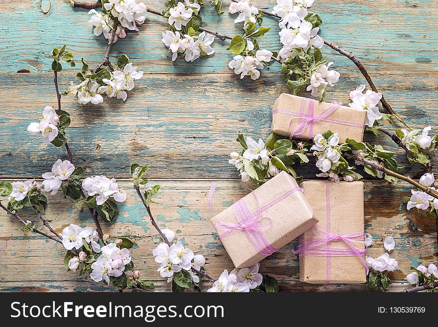 Blossoming apple tree branches with gift boxes on wooden background. Copy space. Spring flowering branch.