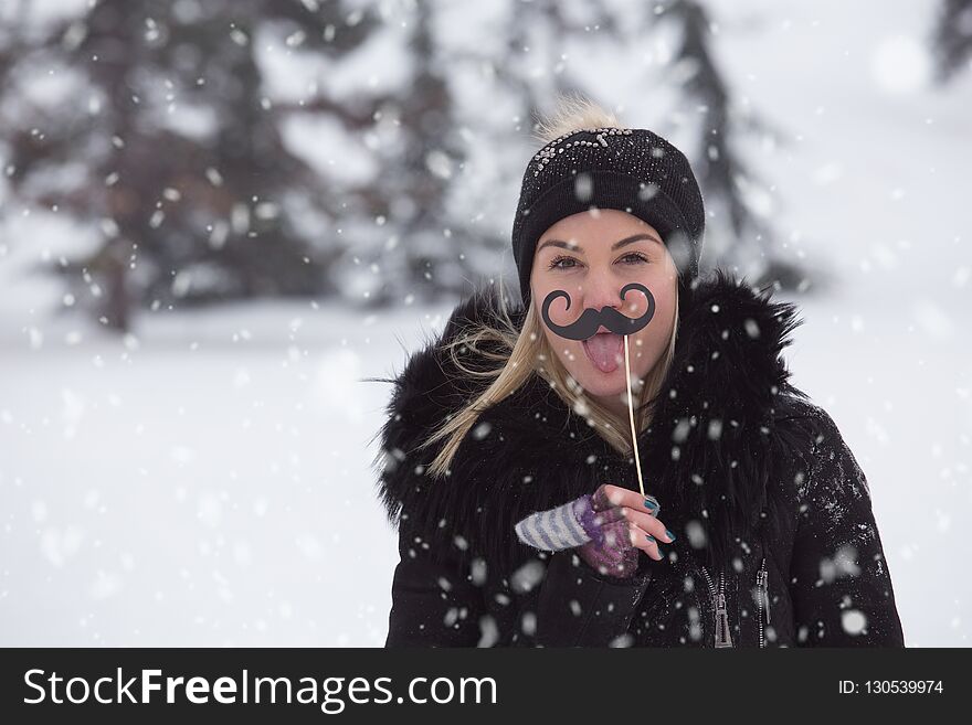 Portrait Of Young Women With Mustache Paper Props On Snowy Day.