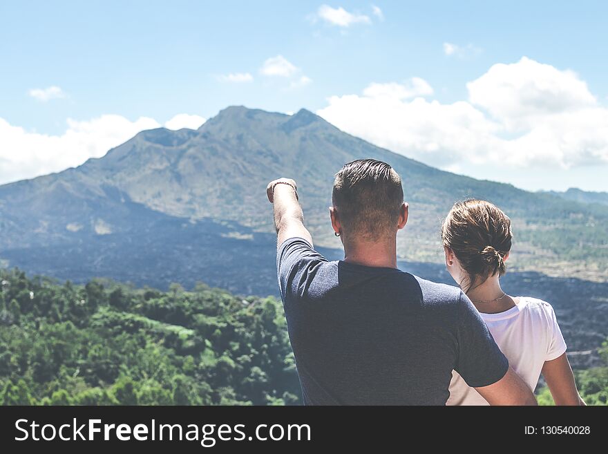 Young couple standing on a mountain background. Volcano Batur, Bali island.