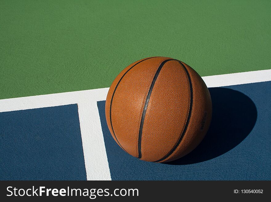 Leather basketball on colorful outdoor court - great background for your hoops related event. Leather basketball on colorful outdoor court - great background for your hoops related event