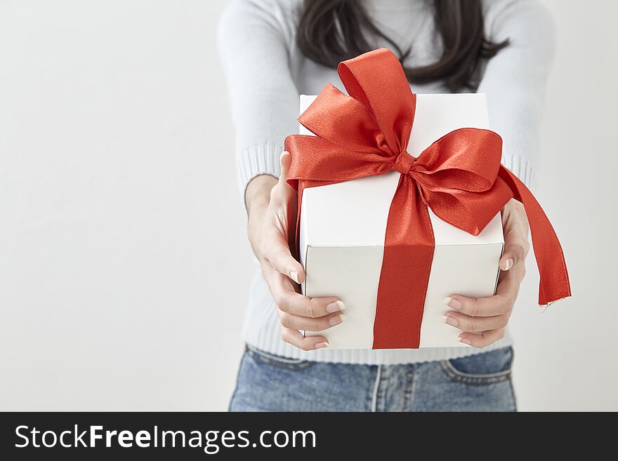 Young Asian woman show OK with a gift box on bright gray wall background. Young Asian woman show OK with a gift box on bright gray wall background
