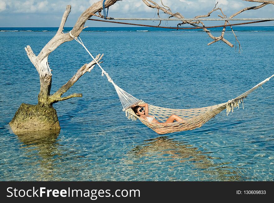 Woman relaxing in the swing in the paradise turquoise sea