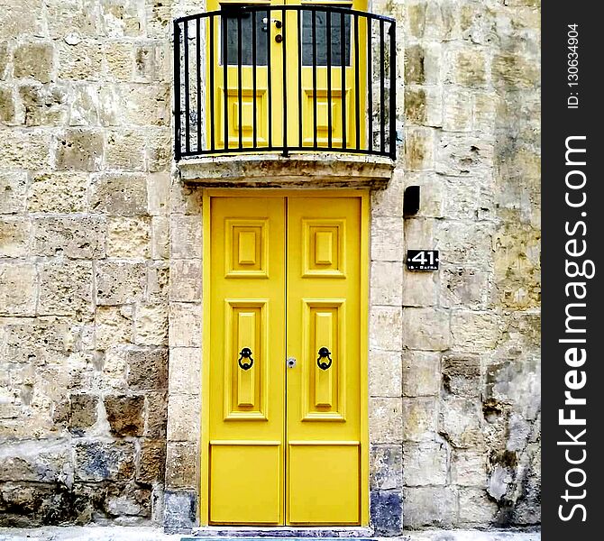 Old wooden doors painted yellow with antique cast iron handles. Entrance doors to the apartment in Malta. Old wooden doors painted yellow with antique cast iron handles. Entrance doors to the apartment in Malta