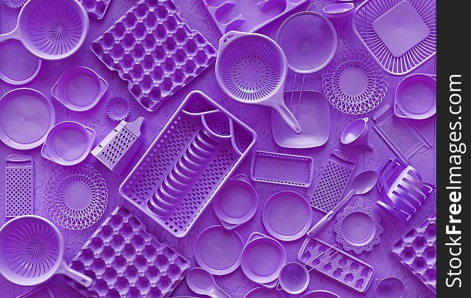 Close up flat lay of different purple violet color painted kitchen utensils and tools, grater, spoon, egg carton, plastic disposable plates, elevated top view, directly above. Close up flat lay of different purple violet color painted kitchen utensils and tools, grater, spoon, egg carton, plastic disposable plates, elevated top view, directly above