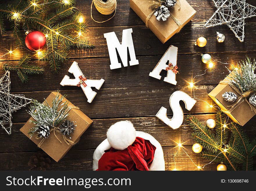 Flat lay Christmas background Word Xmas and wreath made of Christmas decoration and christmas lights on dark wooden table top view. Flat lay Christmas background Word Xmas and wreath made of Christmas decoration and christmas lights on dark wooden table top view