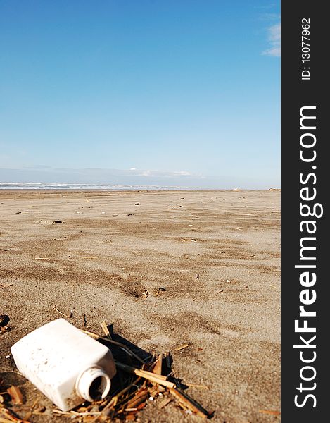 A plastic container littering a sandy beach. A plastic container littering a sandy beach.