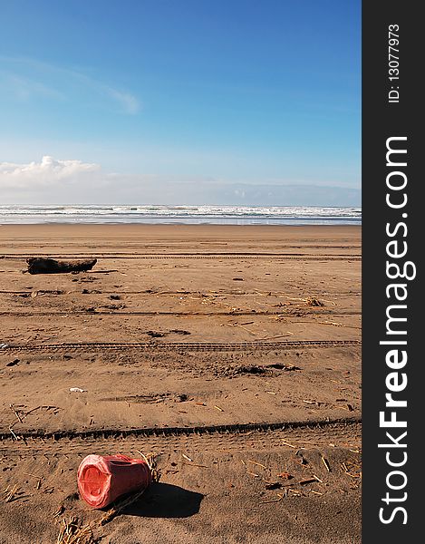 A plastic coffee container littering a sandy beach. A plastic coffee container littering a sandy beach.