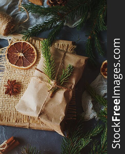 Christmas or New Year composition with handmade gifts, dry oranges, cinnamon, fir tree on dark stone table. Holidays preparations