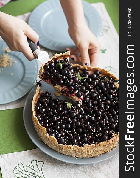 Berry sand pie: the girl slicing the cake and spreads the pieces on the blue plates.