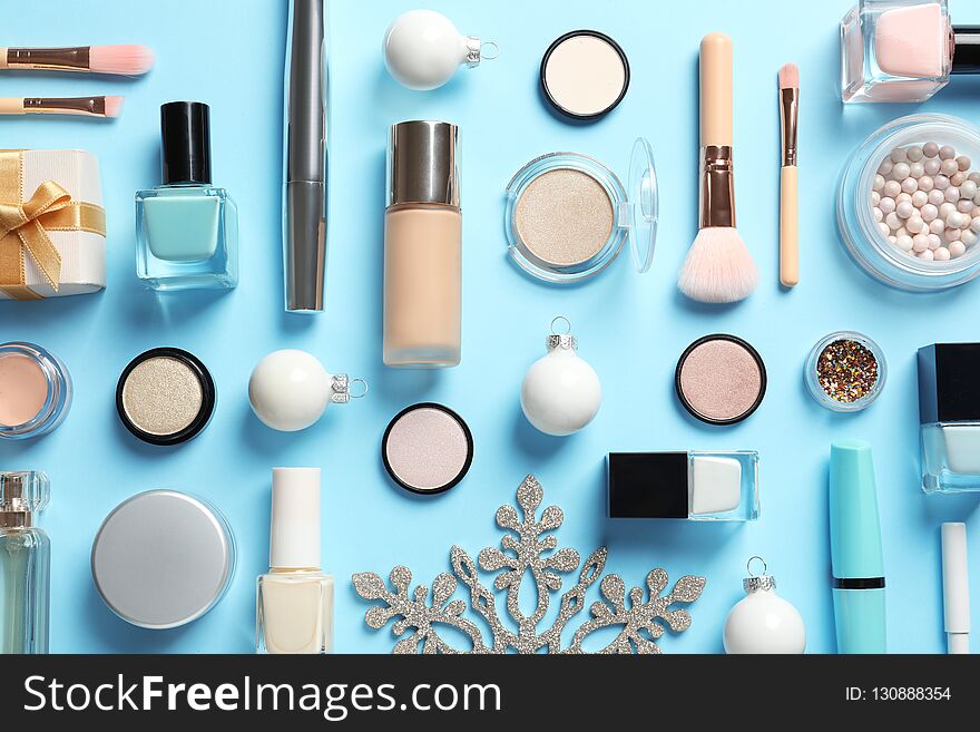 Flat lay composition with makeup products and Christmas decor on color background