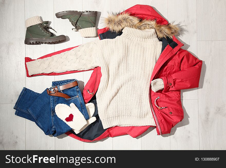 Set of stylish winter outfit on wooden background, flat lay