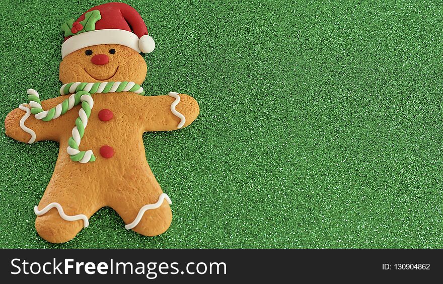 Gingerbread man with red Santa hat green and white scarf on a green background with writing space