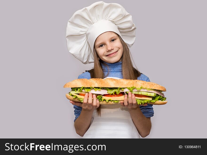 Happy little girl with hot dog and chef uniform isolated on white background. Kid chef.