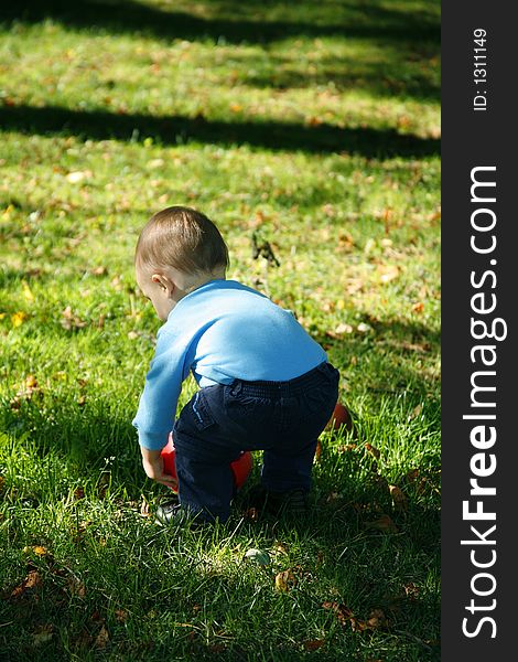 Adorable little boy squatting down to pick up his ball. Adorable little boy squatting down to pick up his ball