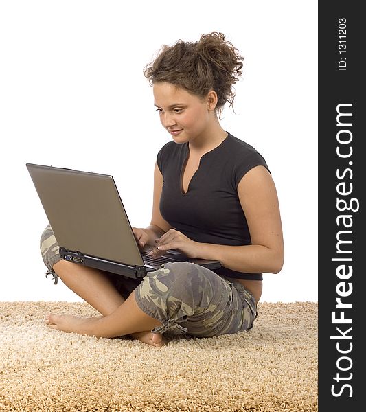 Isolated on white female teenager sitting on the carpet with laptop