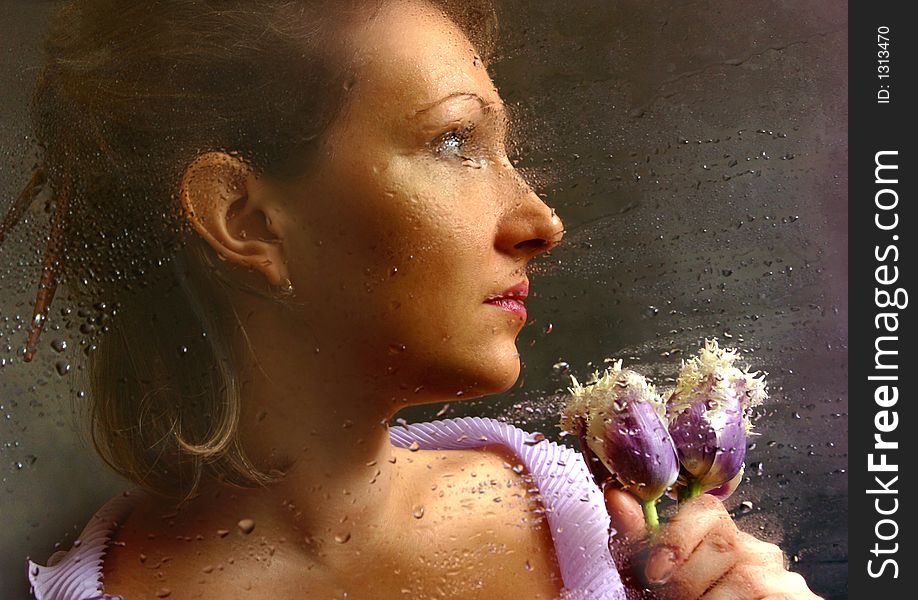 The woman with tulips behind of a damp window. The woman with tulips behind of a damp window