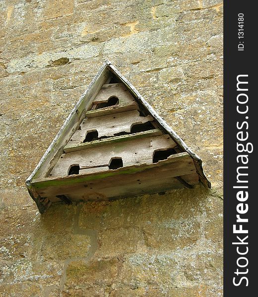 Wooden triangular dovecote mounted onto limestone block wall