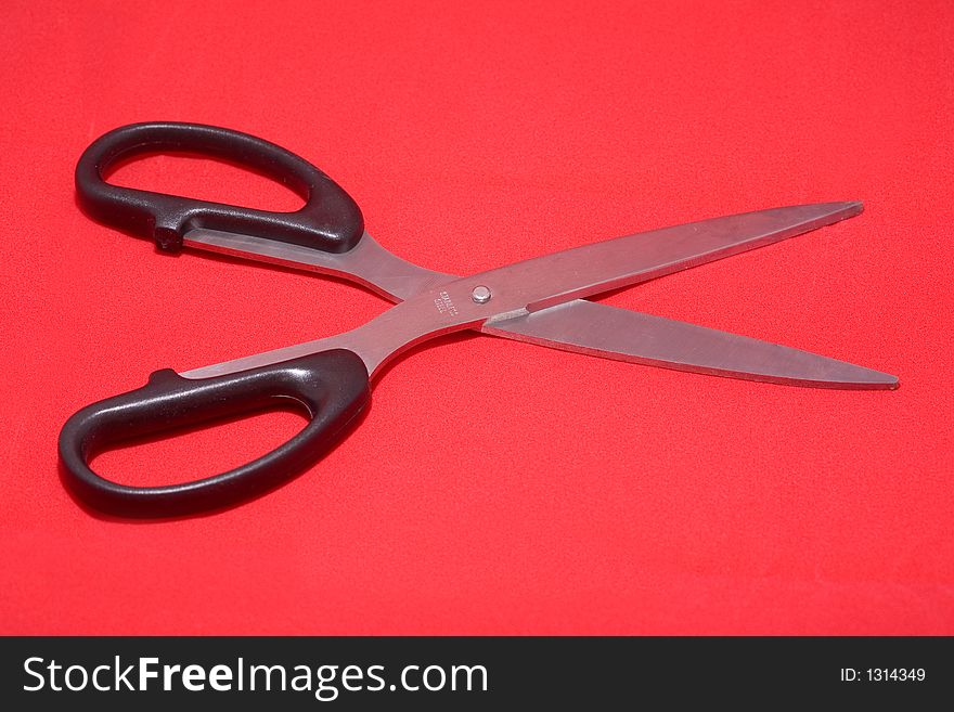 Open scissors isolated in red background