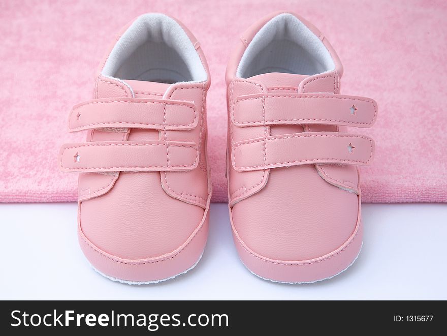 Pink baby shoes on pink towel. Pink baby shoes on pink towel