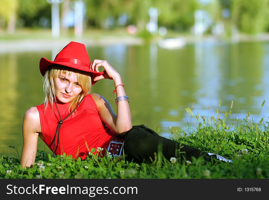 Beautiful sexy blonde cowgirl in the countryside with red hat