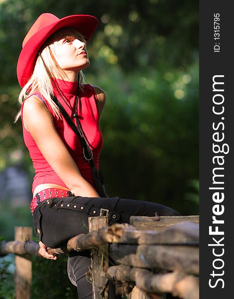 Beautiful sexy blonde cowgirl in the countryside with red hat