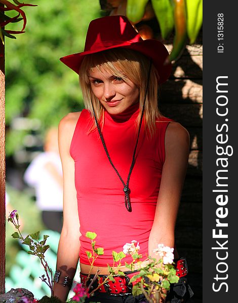 Beautiful sexy blonde cowgirl in the countryside with red hat