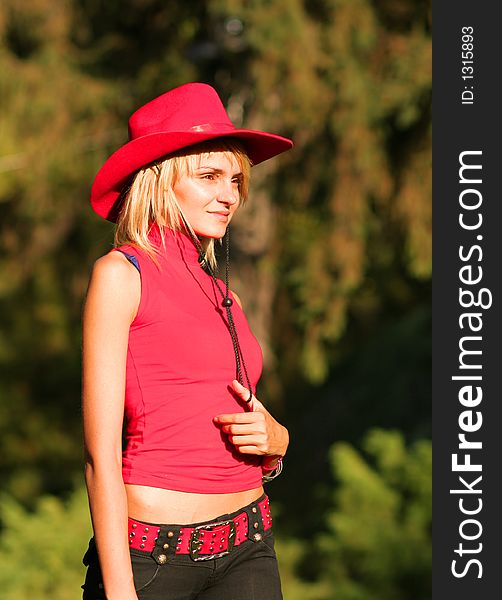 Beautiful sexy blonde cowgirl in the countryside with red hat