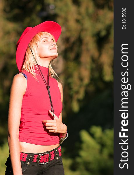 Beautiful sexy blonde cowgirl in the countryside with red hat