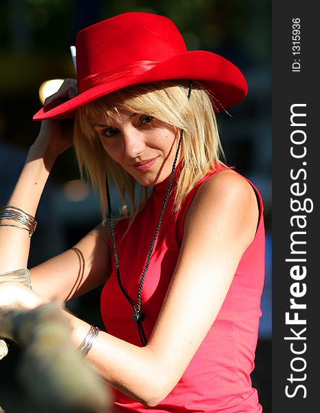 Beautiful sexy blonde cowgirl in the countryside with red hat