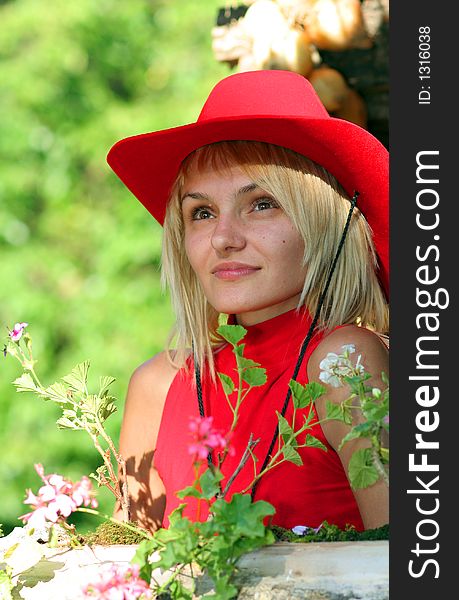Beautiful sexy blonde cowgirl in the countryside with red hat