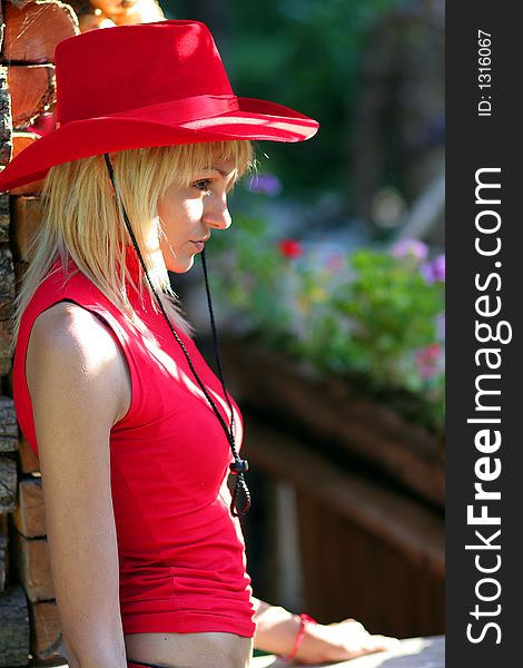 Beautiful blonde cowgirl in the countryside with red hat. Beautiful blonde cowgirl in the countryside with red hat