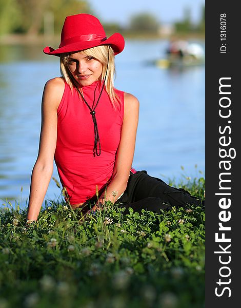 Beautiful sexy blonde cowgirl in the countryside with red hat