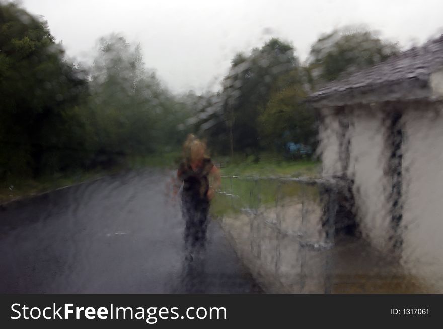 A young woman walking through the pouring rain. (Taken through a rain drenched glass window and therefore a blurred picture enhancing the visual effect of the downpour). A young woman walking through the pouring rain. (Taken through a rain drenched glass window and therefore a blurred picture enhancing the visual effect of the downpour).